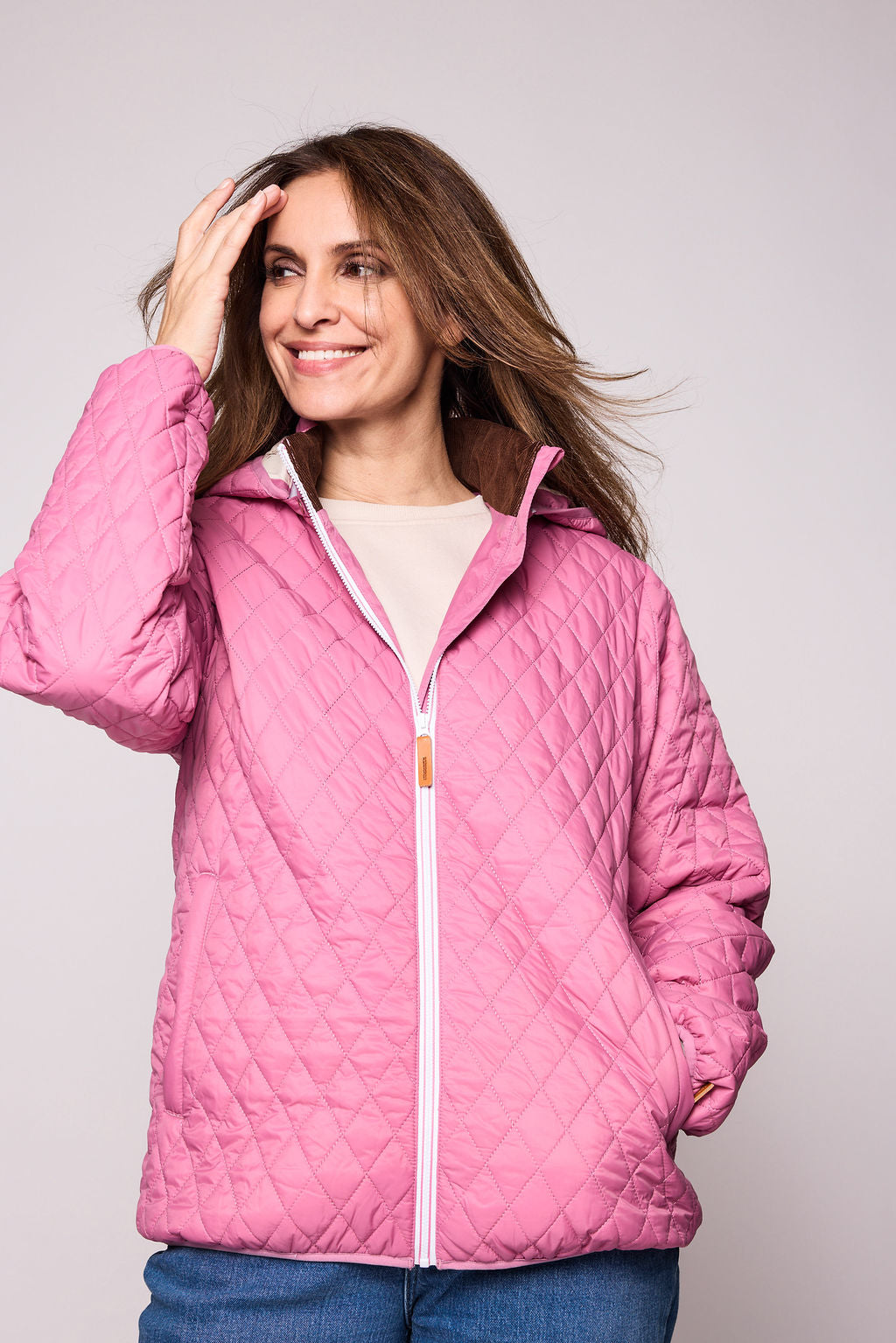 Women's pink puffer jacket for fall and winter with removable hood, insulated lining, and water-resistant outer shell