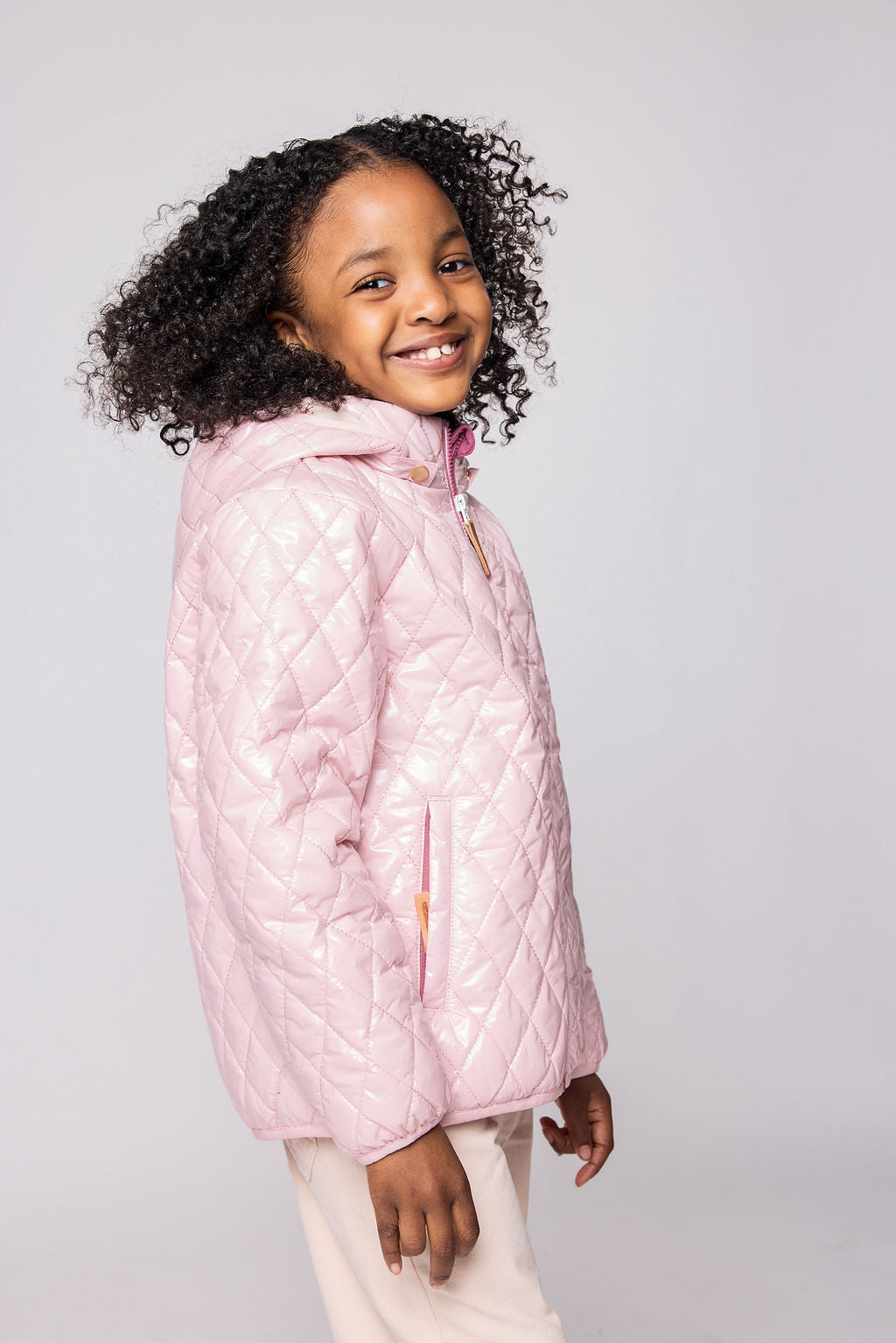 Girls and women shiny light pink puffer jacket for fall and winter, designed as a warm in-between layer with removable hood, insulated core, and water-resistant fabric