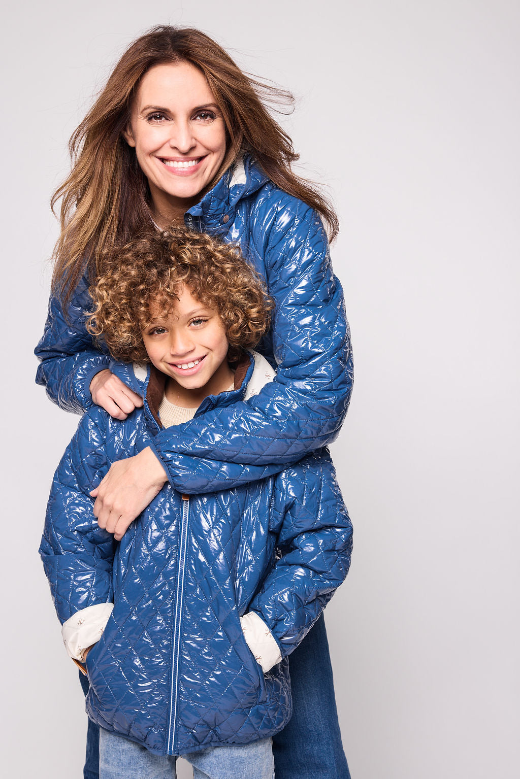 Kids and women shiny blue puffer jacket for fall and winter, designed as a warm in-between layer with removable hood, insulated core, and water-resistant fabric