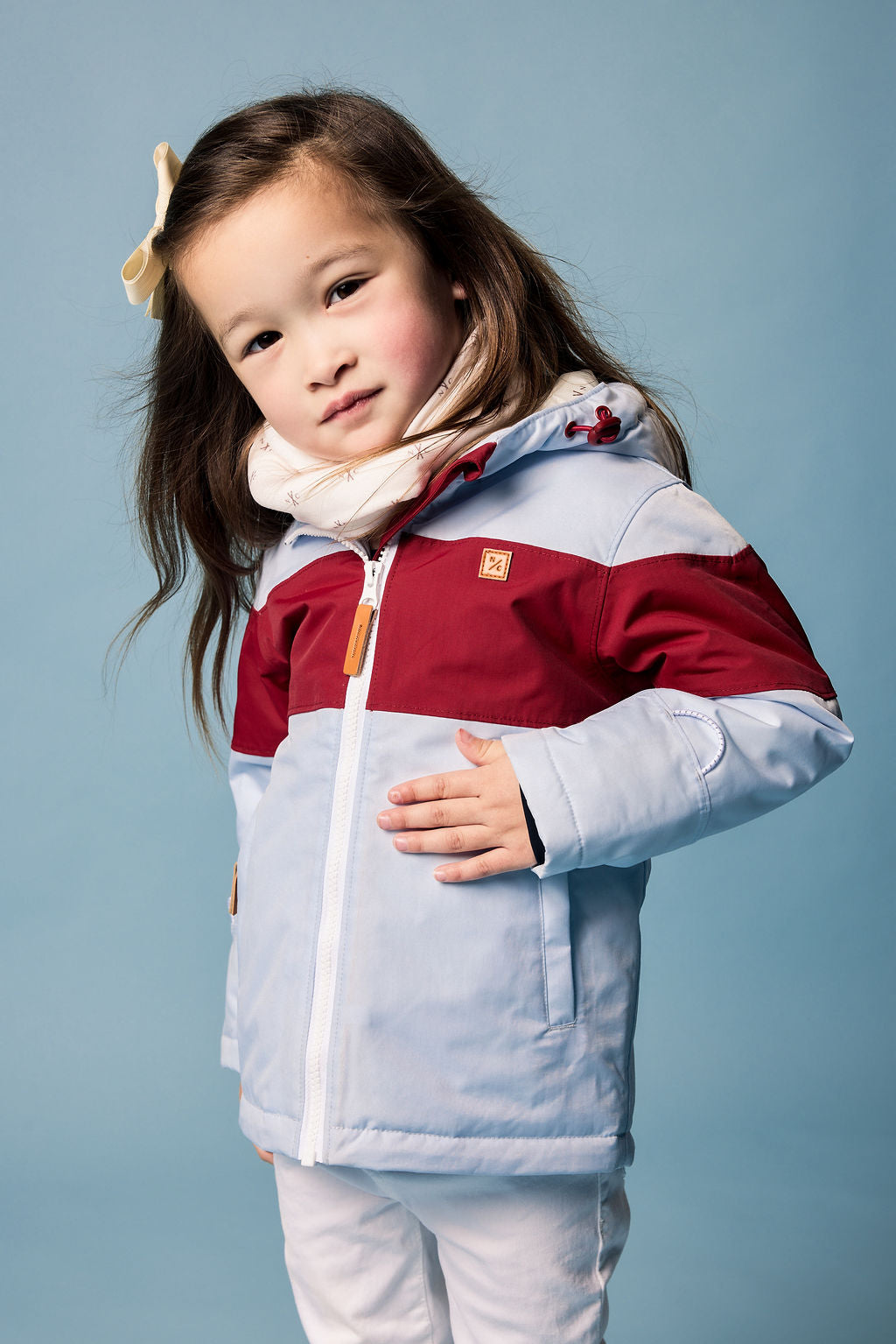 Kids red and light blue winter coat for skiing and snow play, with warm insulation and waterproof outer shell for full cold weather protection and hood