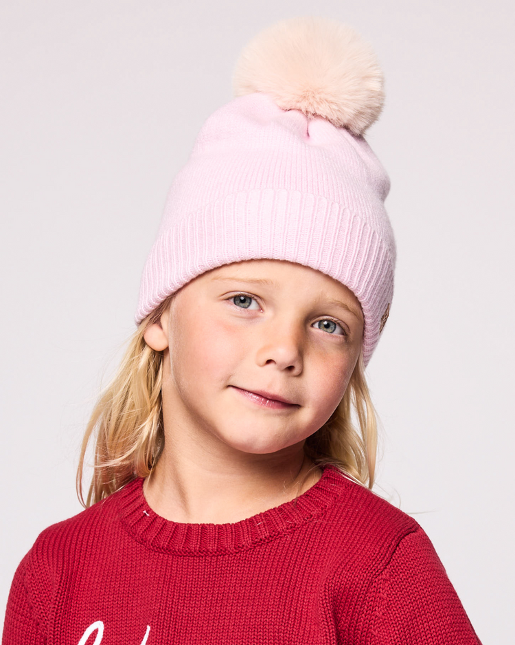 Classic Knit Pom Pom Hat for Kids and Women’s sizes in light pink crafted with soft knit fabric, luxe faux fur pom detail, and winter-ready durability for everyday adventures. It's so soft it feels like cashmere.