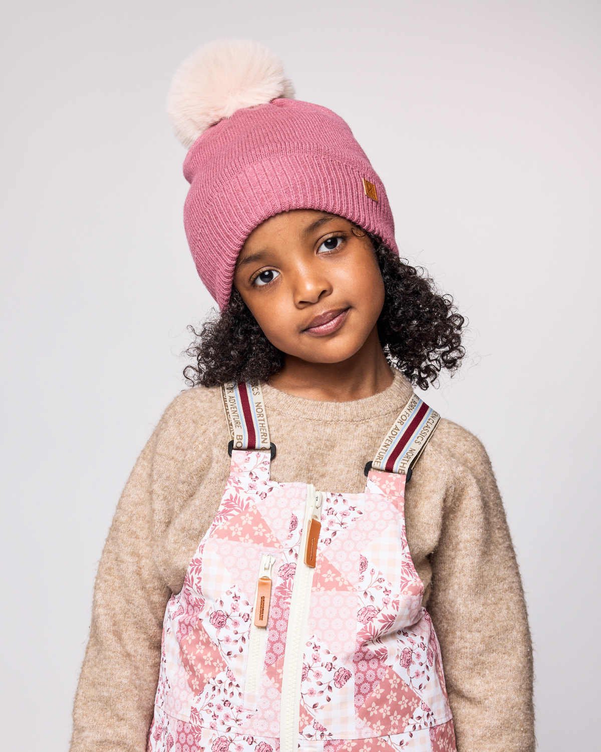 Classic Knit Pom Pom Hat for Kids and Women’s sizes in rose pink crafted with soft knit fabric, luxe faux fur pom detail, and winter-ready durability for everyday adventures. It's so soft it feels like cashmere.
